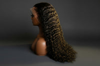 Curly black wig on a mannequin head against a white background
